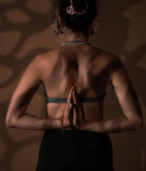 Woman in a calm yoga pose, embodying balance and serenity in a dark studio.
